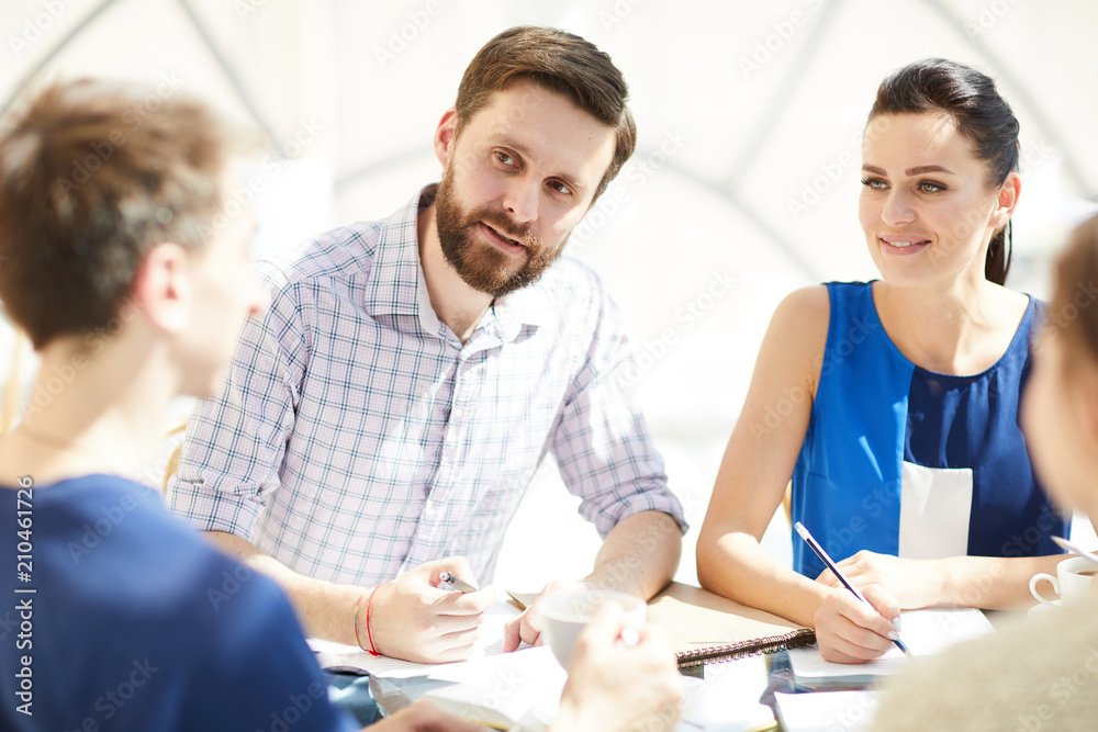 Bearded businessman looking at one of colleagues during discussion of new working points