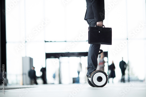 Side view of businessman in formalwear standing on hoverboard and moving straight photo