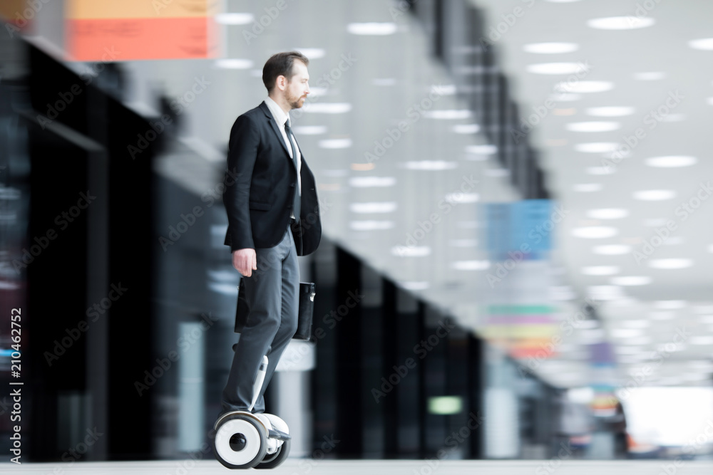 Obraz premium Young businessman on hoverboard hurrying for briefing or conference inside modern building
