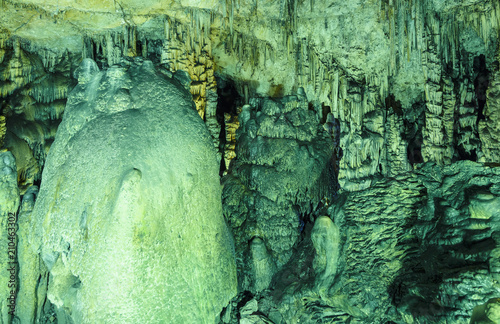 fantastic texture of round curves of stalactites in the cave, green light photo