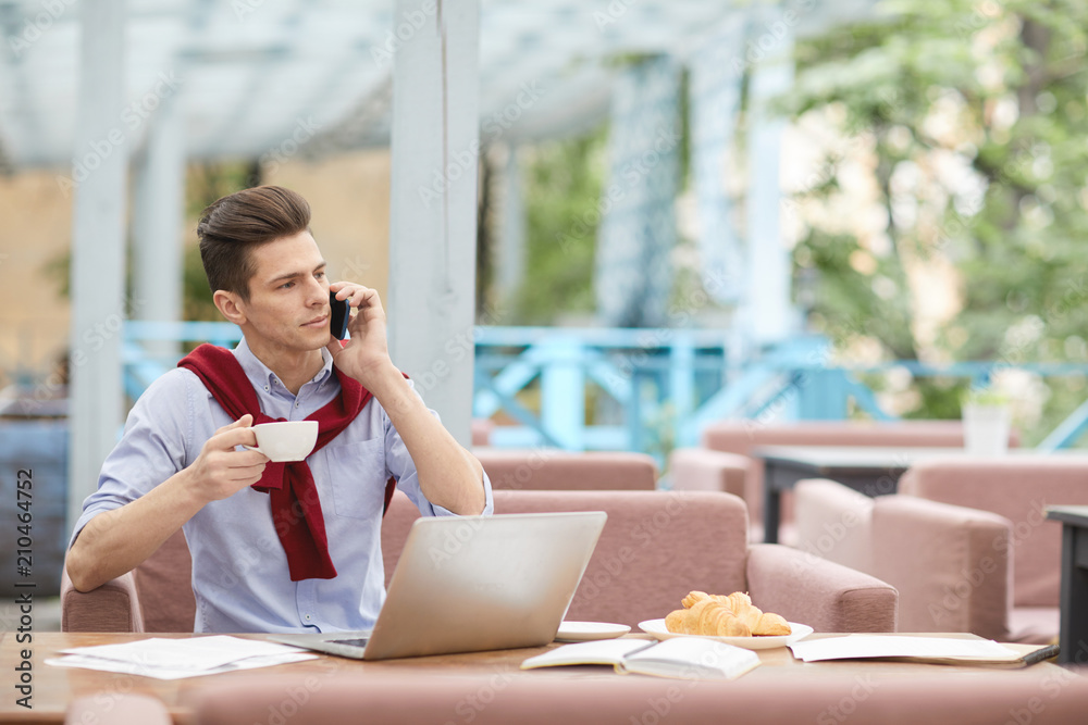 Busy man with smartphone and cup of tea having break in outdoor cafe in the middle of the day Busy man with smartphone and cup of tea having break in outdoor cafe in the middle of the day