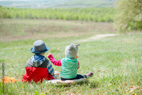 Little boy and baby girl sitting on a background of green landscape. photo