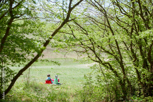 Little boy and baby girl sitting on a background of green landscape. photo