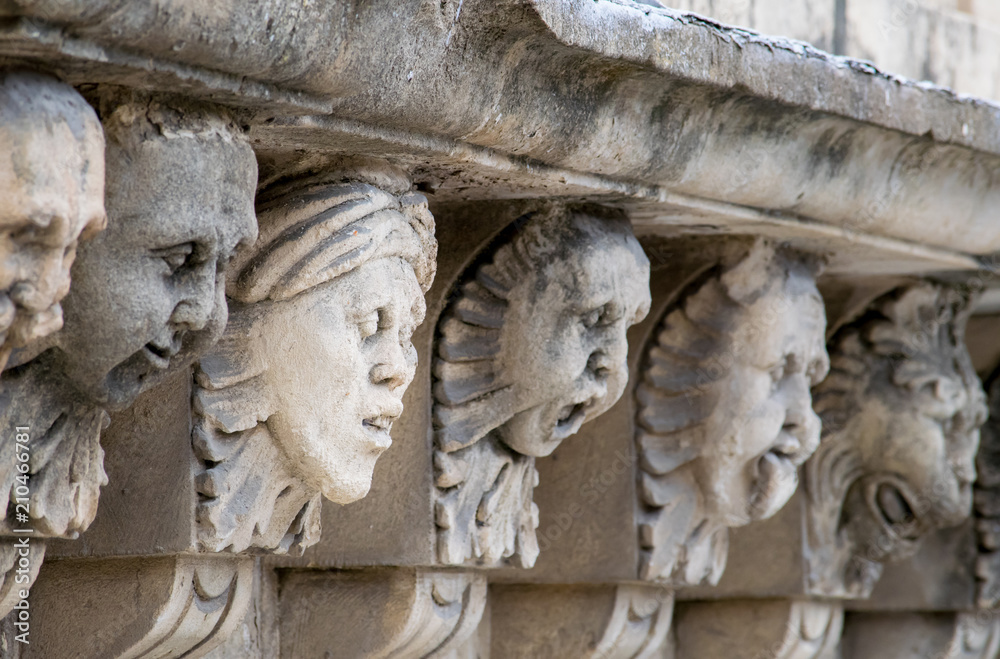Closeup view of mascarons with funny faces under the balcony of a baroque palace in the province of Syracuse, Sicily Closeup view of mascarons with funny faces under the balcony of a baroque palace in the province of Syracuse, Sicily