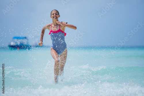Girl in swimsuit runing and having fun on tropical beach photo