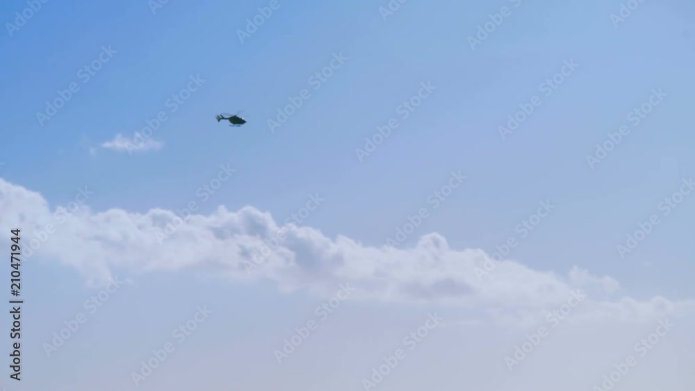silhouette of a helicopter gaining height against a blue sky and clouds silhouette of a helicopter gaining height against a blue sky and clouds