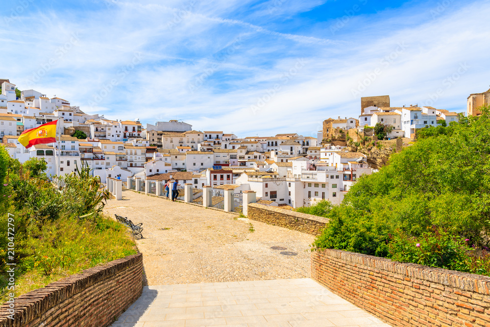 Fototapeta premium SENTINEL DE LAS BODEGAS, SPAIN - MAY 13, 2018: Two men standing on viewpoint and looking at beautiful white village with church on hill. Spain is second most visited by tourists country in Europe.