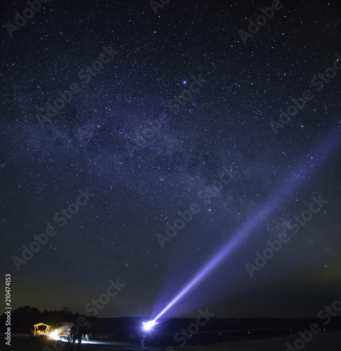  milky way in the background and a person shines flashlight