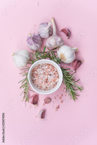 a composition of spices and herbs on a pink background, Himalayan salt with rosemary and garlic