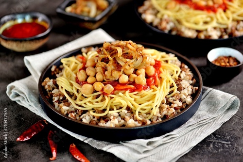 Kushari or Koushari - Egyptian dish of lentils, rice, pasta, chickpeas with tomato sauce and crispy onions. Arabic cuisine