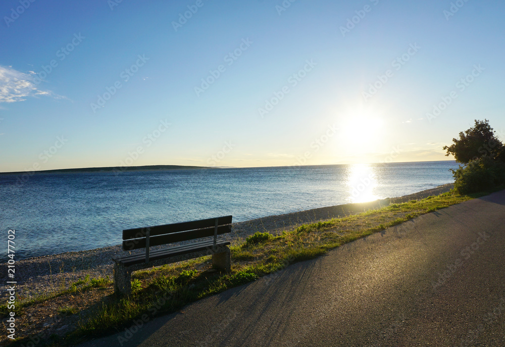 Bench in the seafront at sunset on the early summer windy day