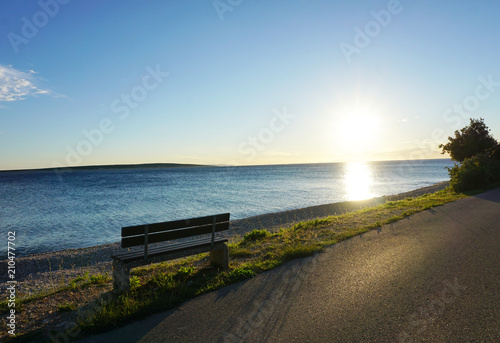 Bench in the seafront at sunset on the early summer windy day © Happy window