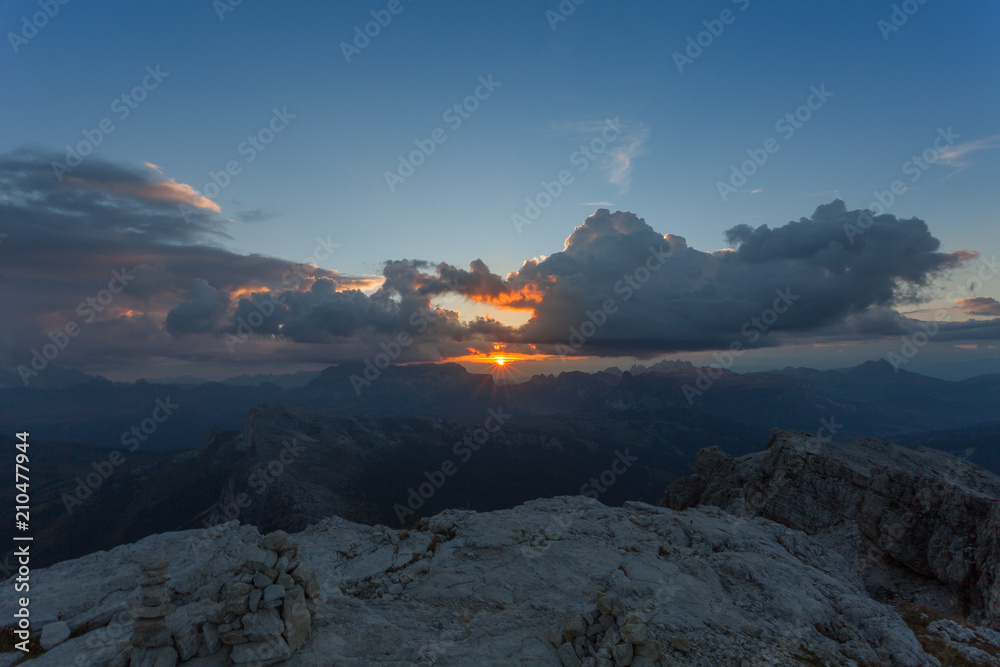 Sun setting between clouds and Dolomite peaks, Lagazuoi, Dolomites, Italy