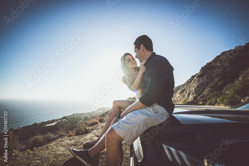 Romantic moment on the cliff in Malibu. Couple watching panorama from their car photo