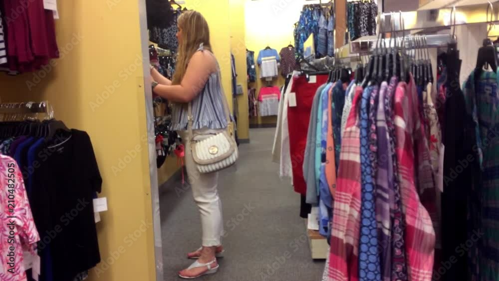 A blonde woman shops in a clothing department store A blonde woman shops in a clothing department store
