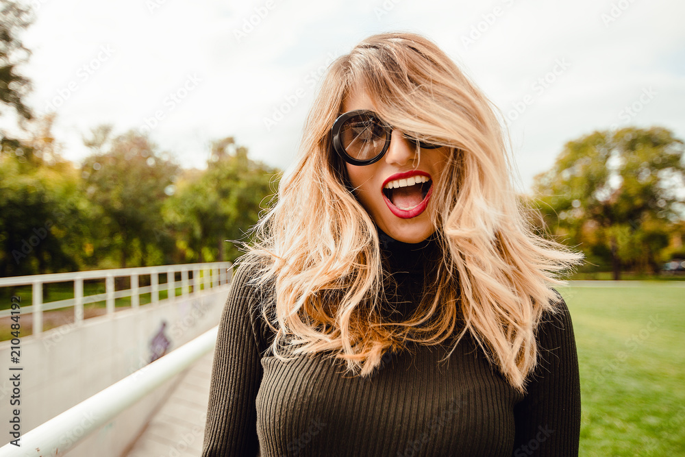 Bright Portrait of young smiling woman in sunglasses relaxing at the park, outdoor portrait hipster girl laugh Bright Portrait of young smiling woman in sunglasses relaxing at the park, outdoor portrait hipster girl laugh