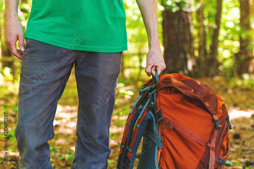 Hiker holding his camping backpack in the forest