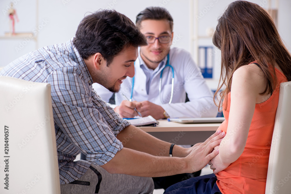 Obraz premium Pregnant woman with her husband visiting the doctor in clinic
