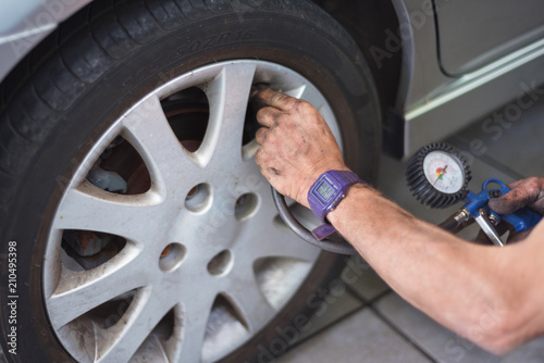 Closeup Of Mechanic At Repair Service Station Checking Tyre Pressure With Gauge