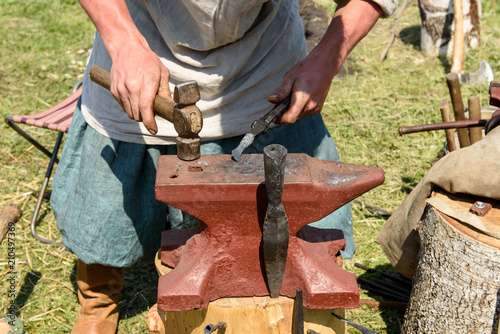 The smith forges an item of metal on the anvil.