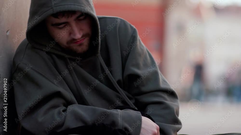 Close up homeless man sitting on street with sign people walk around honeliness sad social cardboard homeless beggar face poverty poor hungry dirty unemployed despair male slow motion portrait Close up homeless man sitting on street with sign people walk around honeliness sad social cardboard homeless beggar face poverty poor hungry dirty unemployed despair male slow motion portrait