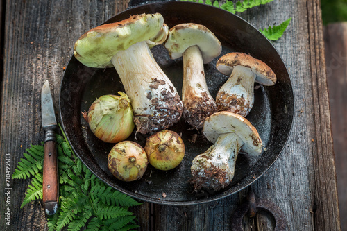 Fresh boletus mushrooms and onion on the pan