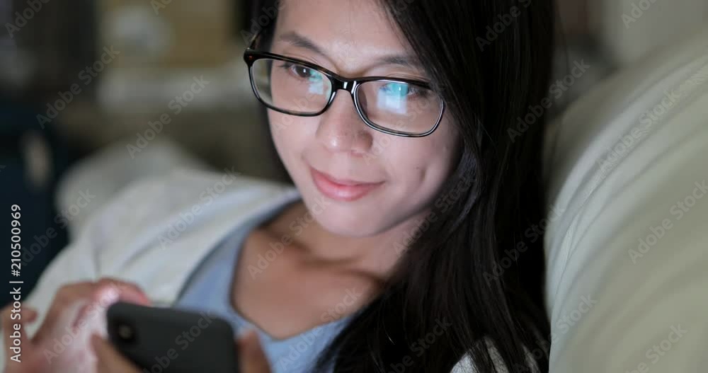 Woman use of smart phone and sitting on sofa at night Woman use of smart phone and sitting on sofa at night