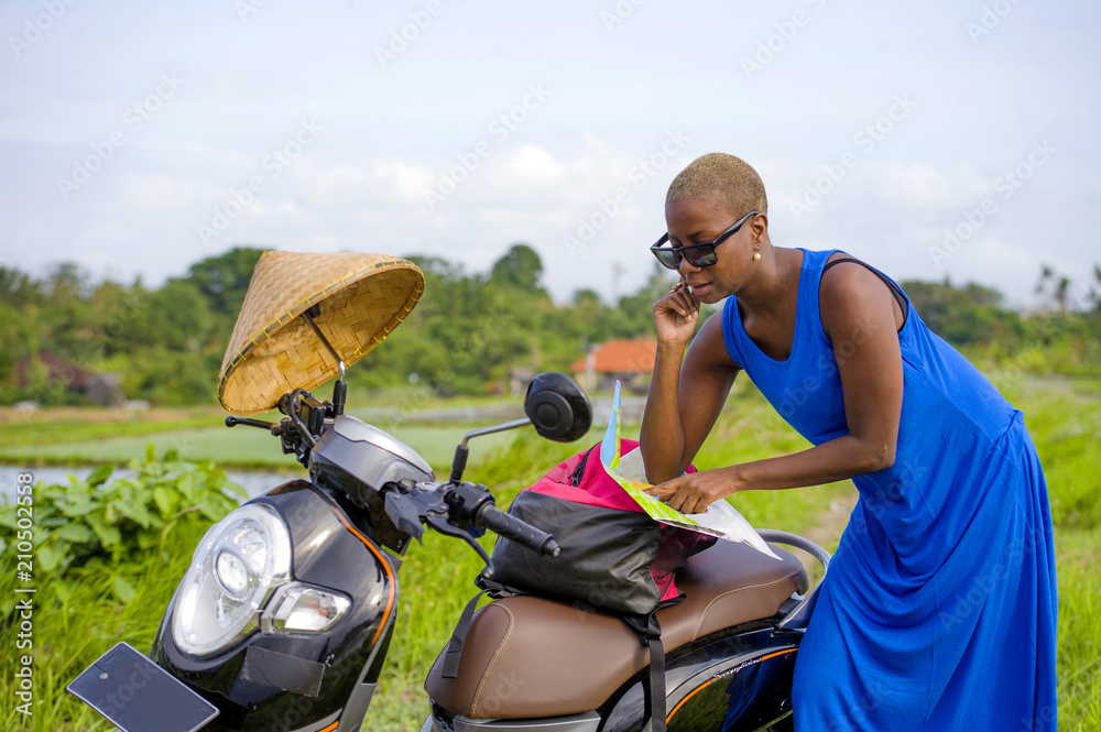 young beautiful black afro american tourist woman with scooter motorbike looking to road map searching the way exploring fields in Asia holidays travel