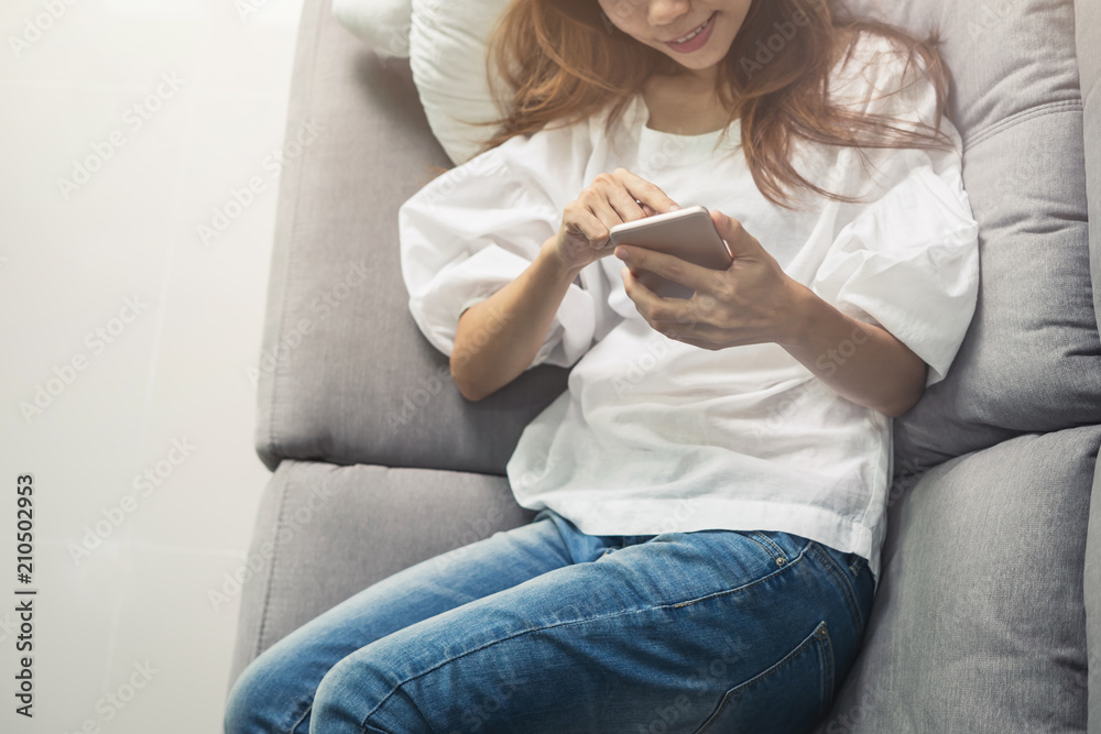 Young woman using smartphone at cozy home on sofa in living room