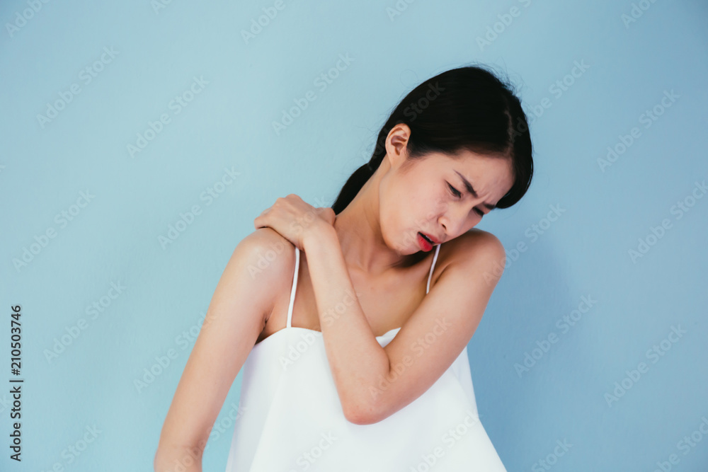 Young Asian woman having chronic neck and shoulder pain isolated over blue background - Healthcare and Medical concept Young Asian woman having chronic neck and shoulder pain isolated over blue background - Healthcare and Medical concept