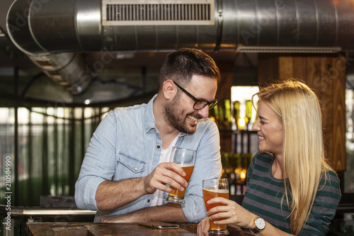 Konstfotografi Young couple looking each other in local pub with glass of beer