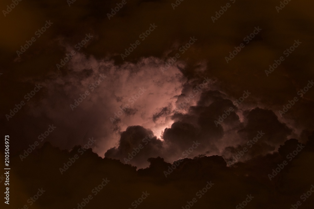 Lightning among the clouds in the night sky