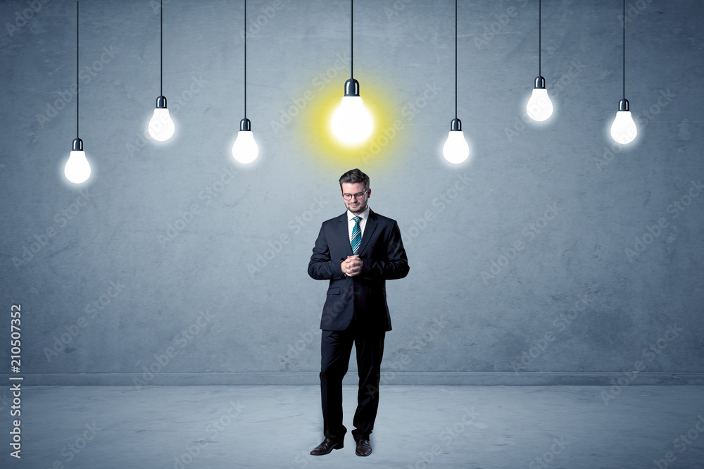 Fototapeta premium Handsome businessman in an empty space with bulbs above and uninspired face 