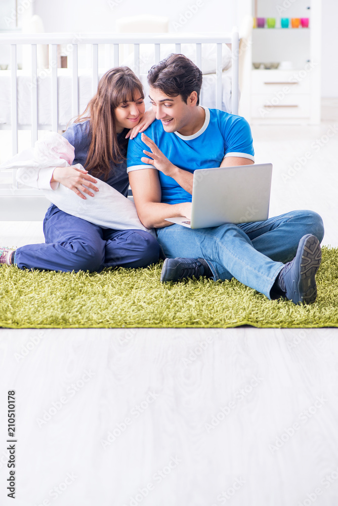 Young parents with their newborn baby sitting on the carpet Young parents with their newborn baby sitting on the carpet