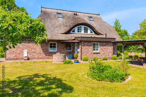 SEEDORF VILLAGE, RUEGEN ISLAND - MAY 28, 2018: Garden with traditional thatched roof house near Seedorf village, Baltic Sea, Germany. Rugen is popular tourist destination due to its rural landscape.
