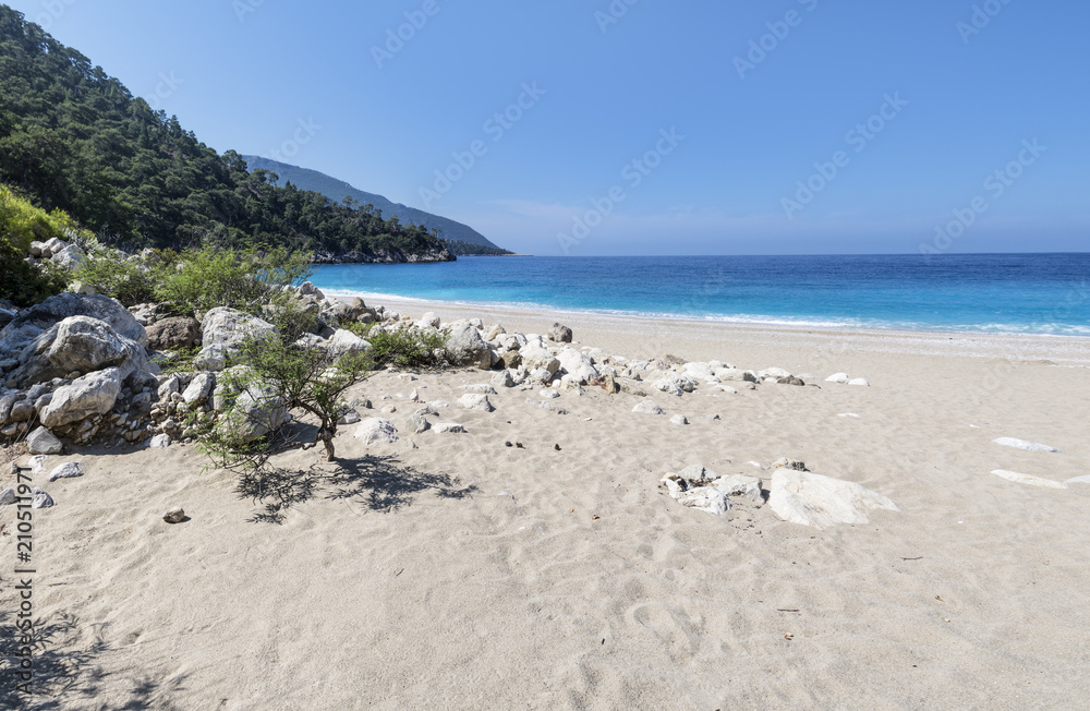 Big sandy beach, turquoise calm sea, blue cloudless sky, green forest and mountains on a summer sunny day