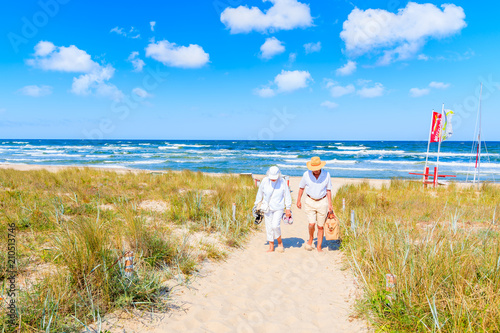 Obraz na płótnie BAABE, RUEGEN ISLAND - MAY 31, 2018: Couple of people walking from beach in Baabe summer resort among sand dunes, Baltic Sea, Germany. Ruegen is popular tourist destination due to its sandy beaches. w salonie