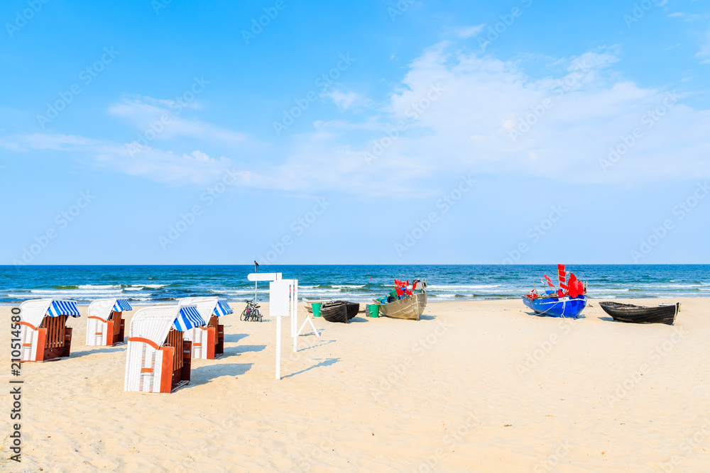 Traditional wooden chairs and fishing boats on sandy beach in Baabe summer resort, Ruegen island, Baltic Sea, Germany Traditional wooden chairs and fishing boats on sandy beach in Baabe summer resort, Ruegen island, Baltic Sea, Germany