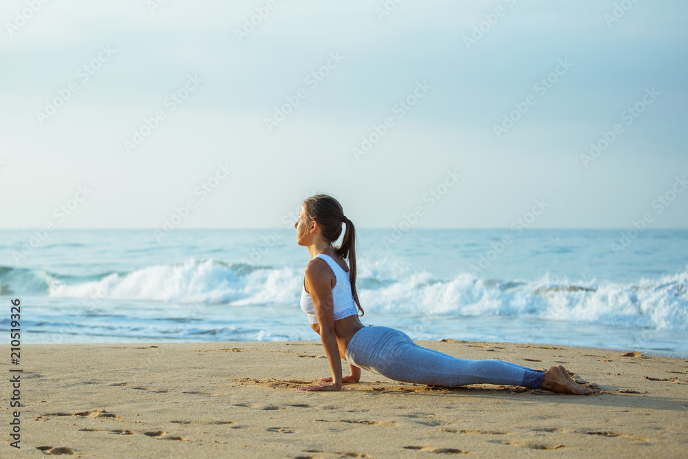 Caucasian woman practicing yoga at seashore of tropic ocean Caucasian woman practicing yoga at seashore of tropic ocean