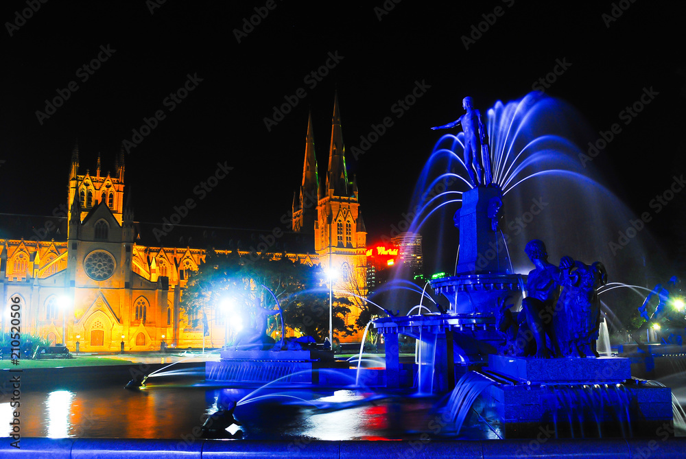 Obraz premium Water fountain in city centre center hyde park downtown Sydney with cathedral church on the background in the evening night for holiday