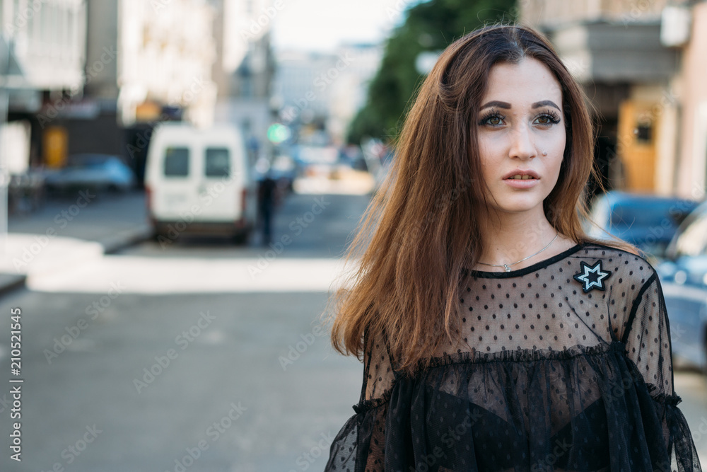 Emotional portrait of Fashion stylish portrait of pretty young woman. city portrait. sad girl. brunette in a black dress. expectation. dreams. girl - night in the middle of the day