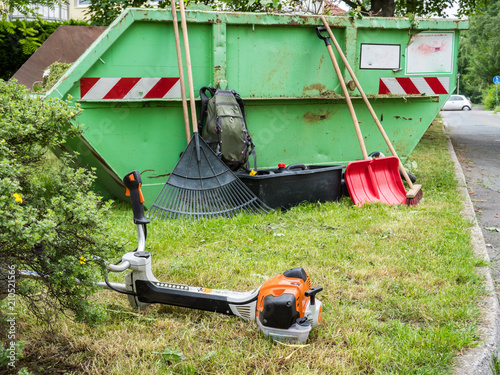 Motorsense und Gartenwerkzeug am Grünabfälle Container