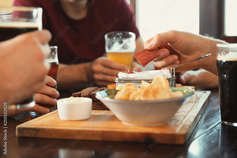 Friends drinking beer and eating snacks at table in pub Friends drinking beer and eating snacks at table in pub