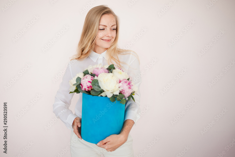 Stylish flower delivery, gift. Woman with flowers in a hat box. Bouquet of peonies.
