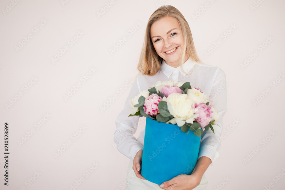 Stylish flower delivery, gift. Woman with flowers in a hat box. Bouquet of peonies.