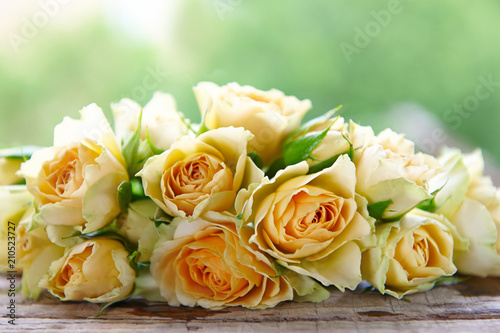 several yellow roses on a wooden table