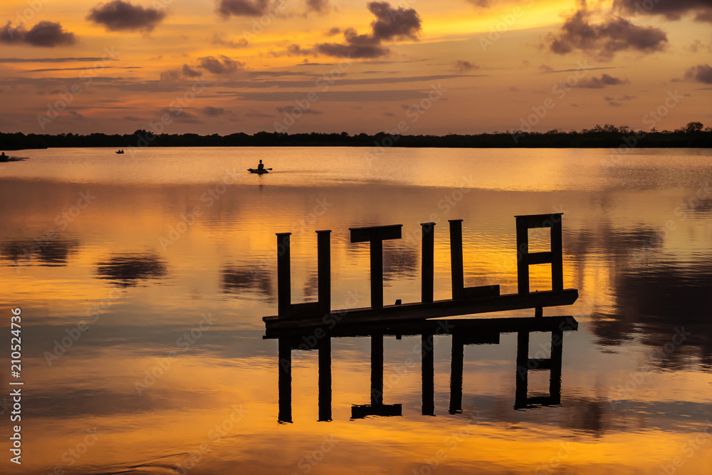 Sunset at a lagoon with Utila letter sign with kanu in background, Utila, Honduras, Central America