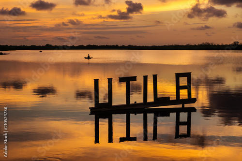 Sunset at a lagoon with Utila letter sign with kanu in background, Utila, Honduras, Central America © Loes Kieboom