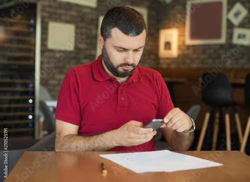 Handsome young man taking photo of documents with smartphone