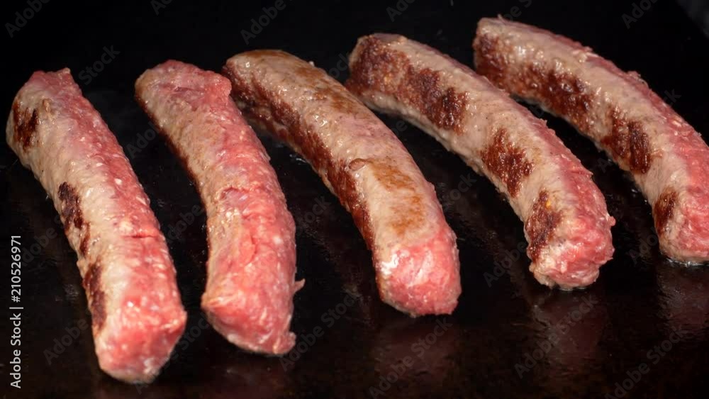 UHD shot of the delicious meat sausages frying on the iron UHD shot of the delicious meat sausages frying on the iron